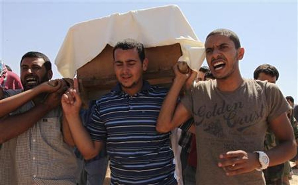 Líbios carregam caixão de rebelde morto na área de Brega por forças leais a Kadafi, durante funeral em Benghazi | Reuters