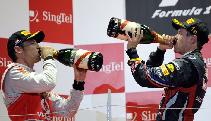 Jenson Button (esq.) admite que o título da temporada está muito distante, mas promete virar pedra no sapado de Vettel (dir.) | Saeed Khan/ AFP