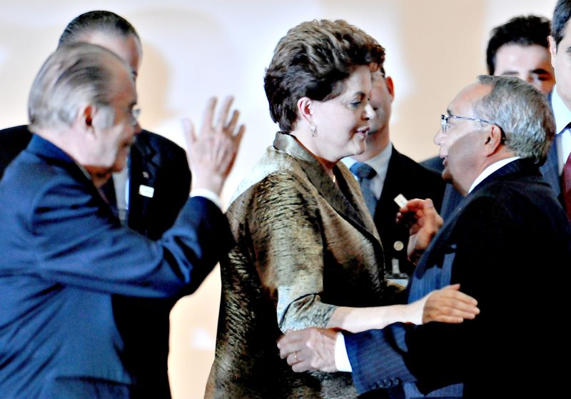 Dilma abraça o novo ministro do Turismo, Gastão Vieira. Ambos são observados por José Sarney (esq.). Presidente do Senado é padrinho de Vieira | Pedro Ladeira/AFP