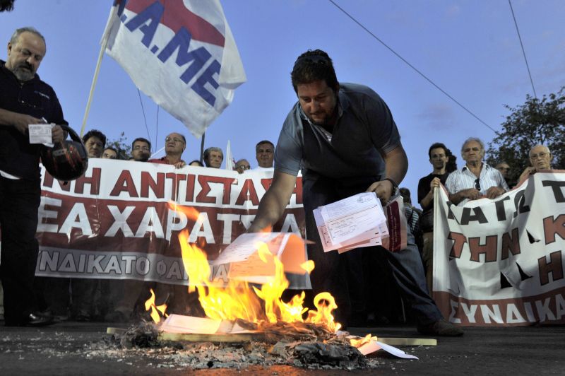 Gregos voltaram a protestar ontem e queimaram boletos de um novo imposto em Atenas | Louisa Gouliamaki/AFP
