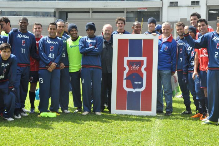 Elenco paranista posa com a bandeira abençoada pelo Papa Bento XVI e doada ao Tricolor por um torcedor | Júlia Abdul-Hak/ Divulgação