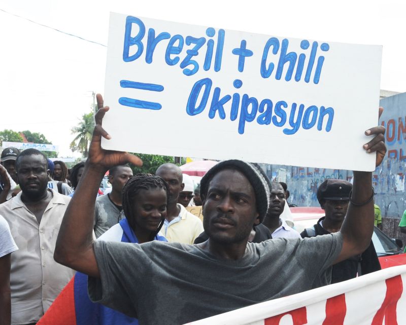 Haitiano exibe cartaz em que condena a presença do Brasil e do Chile no país | Thony Belizaire/AFP