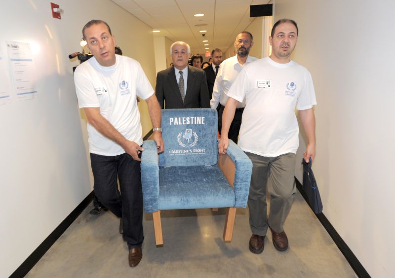 Palestinos carregam um assento simbólico que representa o 194º lugar nas Nações Unidas, que seria ocupado pelo novo Estado | Stan Honda/ AFP