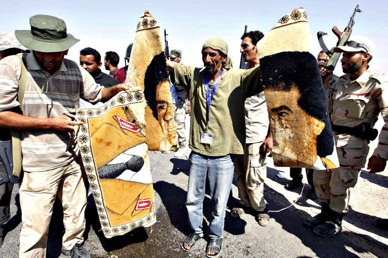 Rebelde exibe partes de tapete com desenho do rosto de Kadafi rasgado | Zohra Bensemra/Reuters
