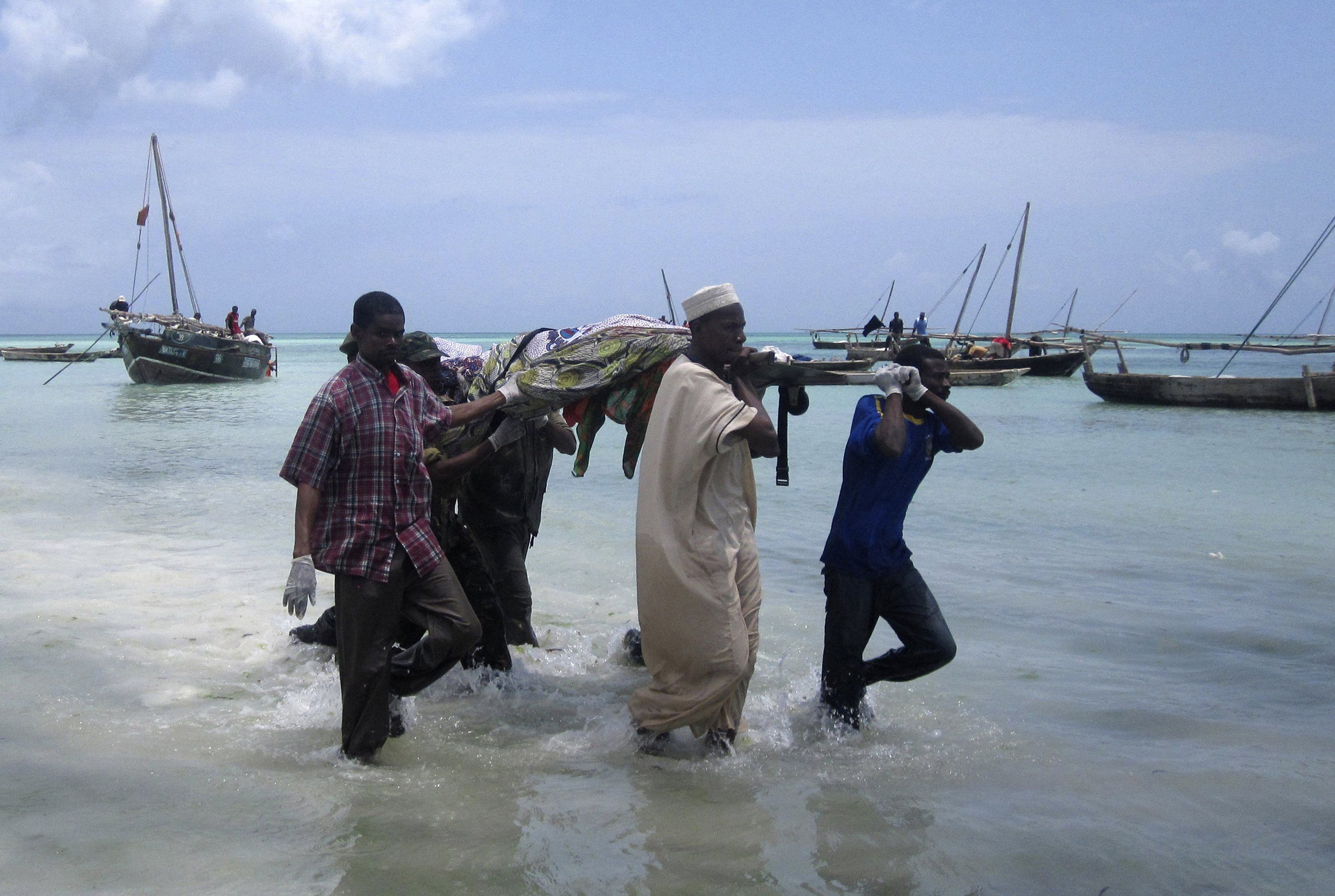 Homens carregam os corpos de vítimas do afundamento de um barcio em Zanzibar, na Tanzânia | REUTERS/Beatrice Spadacini