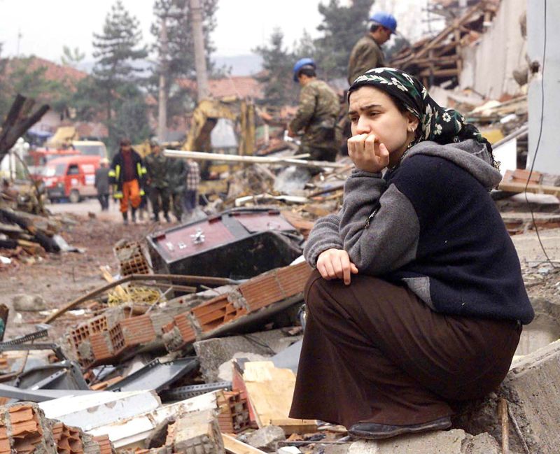 Mulher senta sobre os destroços de sua casa em Kaynasli, na Turquia. Muitas pessoas ainda estão sob os escombros de prédios e casas destruídos pelo terremoto | Mustafa Ozer/AFP