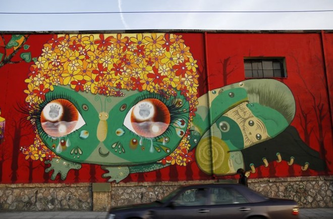 Um dos muros que a artista pintou, em Atenas. Ao lado, uma de suas telas: trânsito constante entre street art e os meios convencionais |