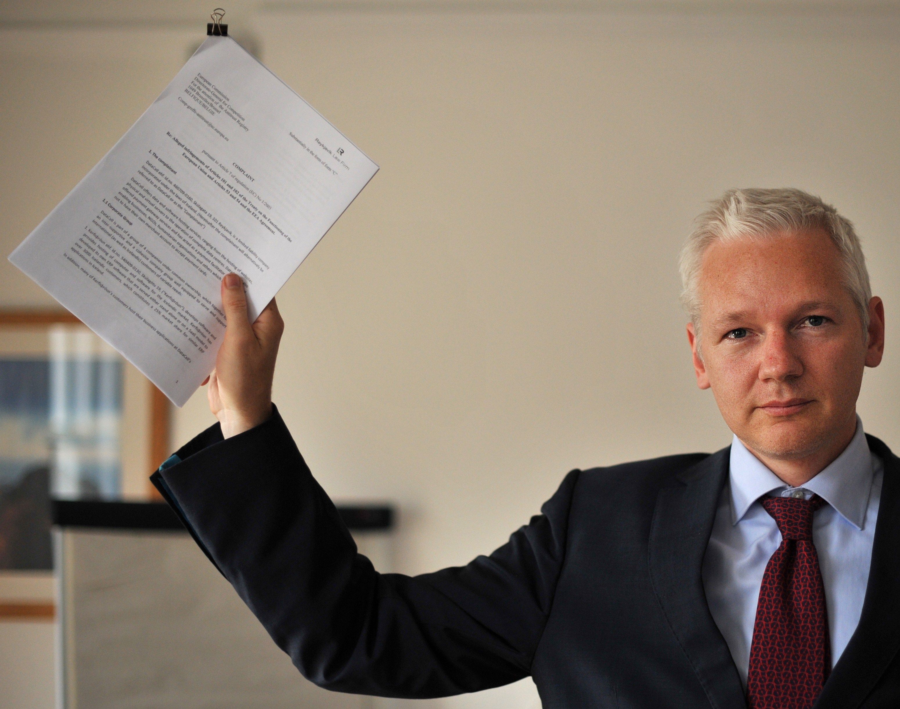 Julian Assange em foto tirada no dia 14 de julho mostrando um documento durante coletiva | AFP PHOTO/BEN STANSALL