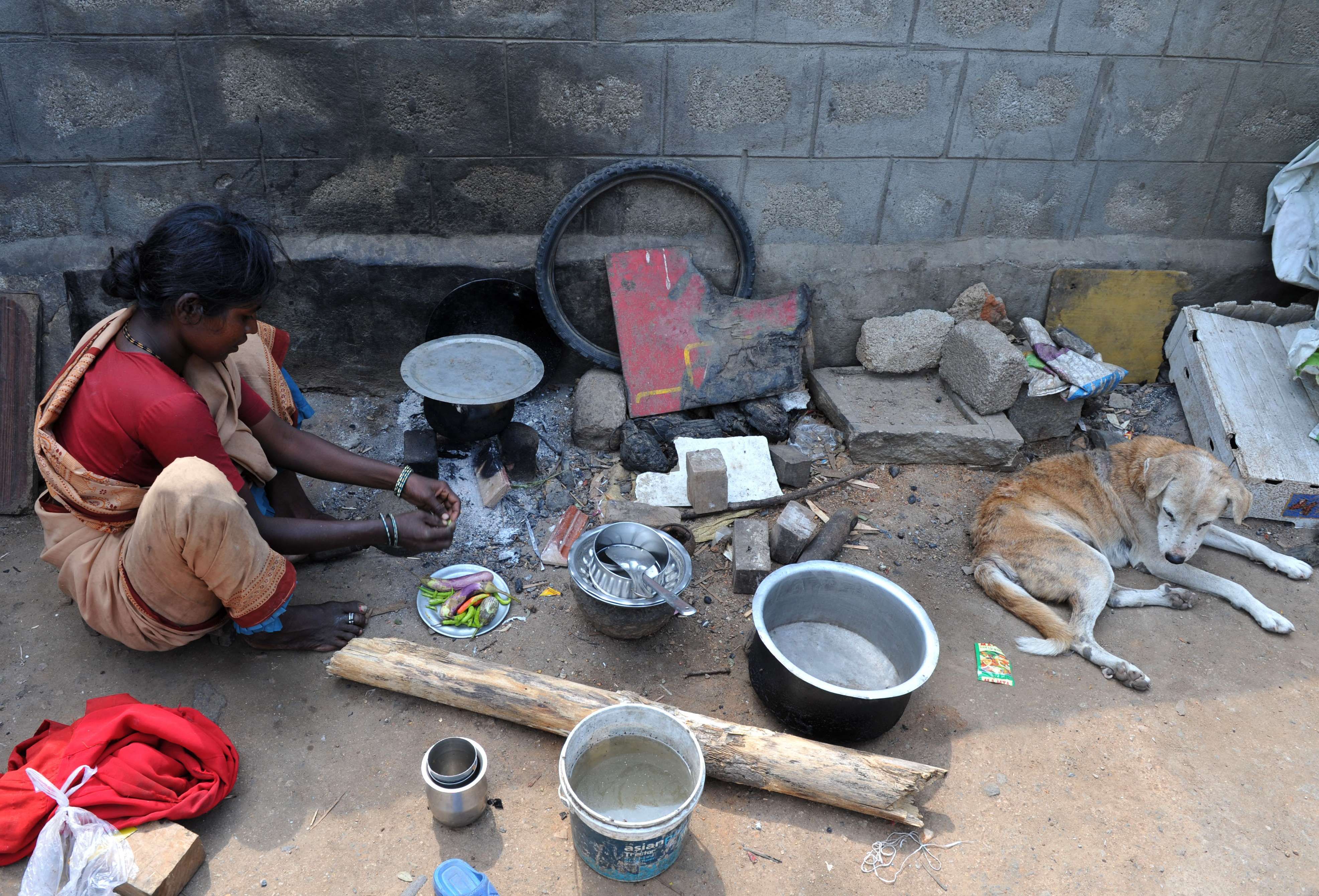 Indiana corta vegetais enquanto cozinha na beira da estrada em um abrigo temporário em Hyderabad | AFP PHOTO/Noah SEELAM