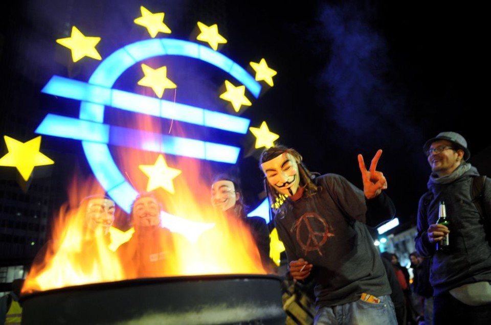 Manifestantes mascarados protestam em frente ao prédio do Banco Central Europeu | AFP