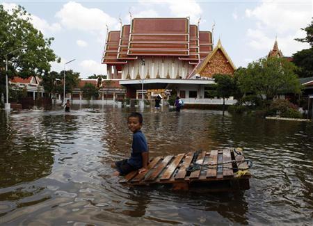 Menino brinca em um templo inundado no bairro de Bang Phlat, em Bangcoc | REUTERS/Chaiwat Subprasom