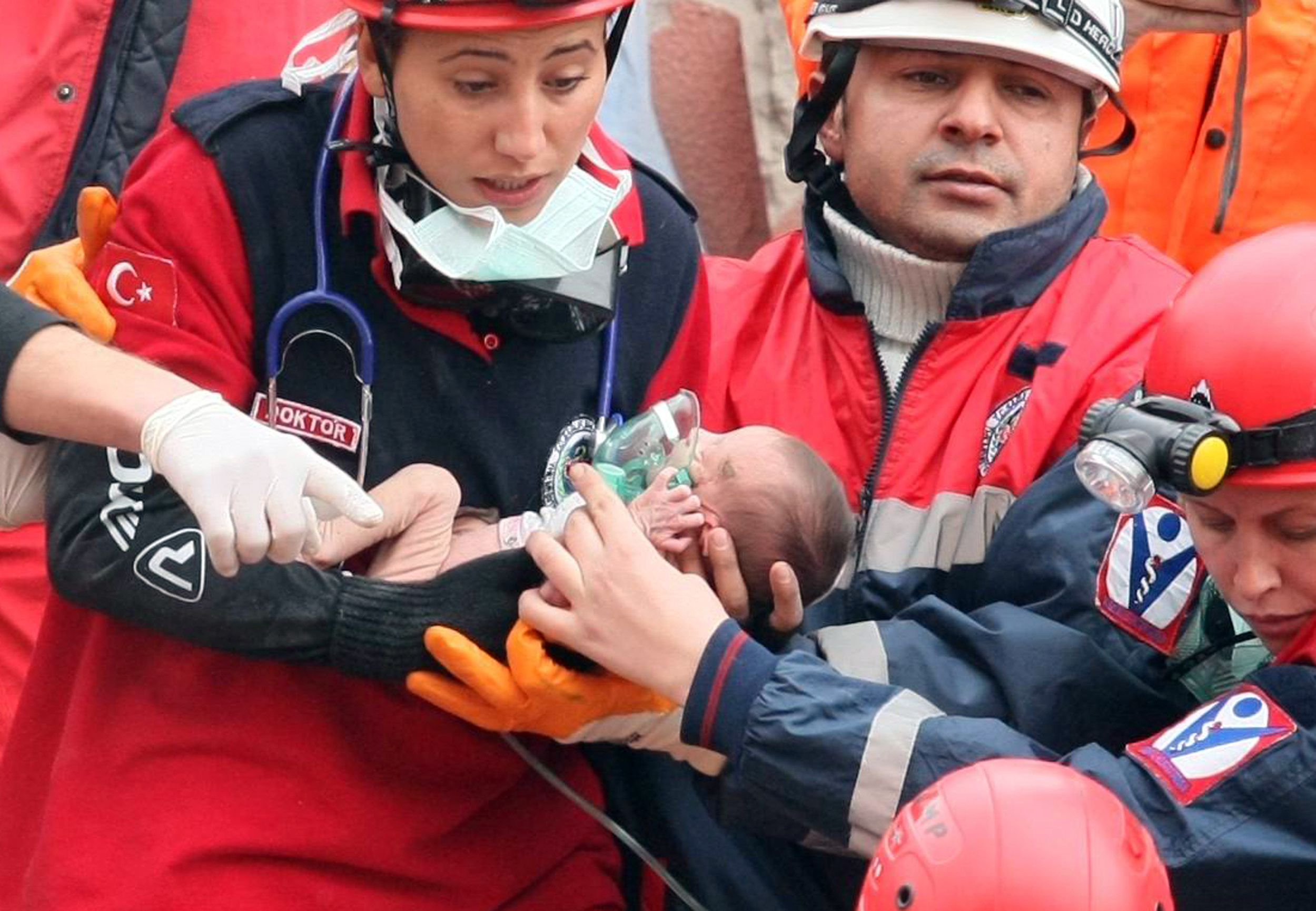 Equipe de resgate carrega Azra Karaduman, um bebê de duas semanas, que estava soterrado por três dias pelos escombros do terremoto que atingiu a Turquia | AFP PHOTO / ADEM ALTAN