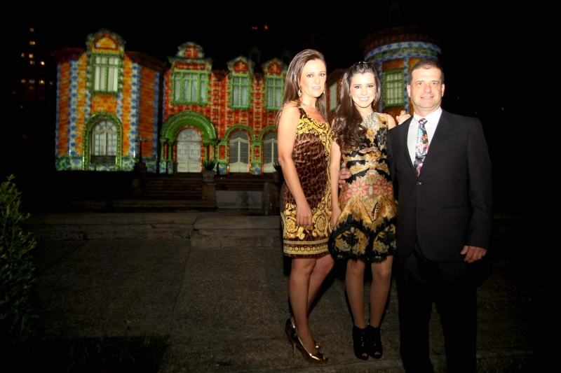 Carol Vosgerau Gusi e os pais Rosana e Geraldo diante do Castelo do Batel sob o efeito do mapping, sistema de projeção de imagens em fachadas de edifícios desenvolvido especialmente para a cinematográfica festa de seus 15 anos, na última sexta-feira. A dupla Dado Dantas e Ilse Lambach criou uma decoração interna e externa que remetia aos castelos do Vale do Loire | Jader da Rocha