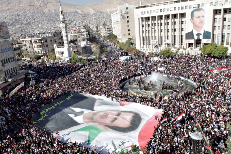Apoiadores do ditador Bashar Assad participam de protesto no centro de Damasco, capital síria, contra a decisão da Liga Árabe de impor sanções ao país | Sana/Reuters