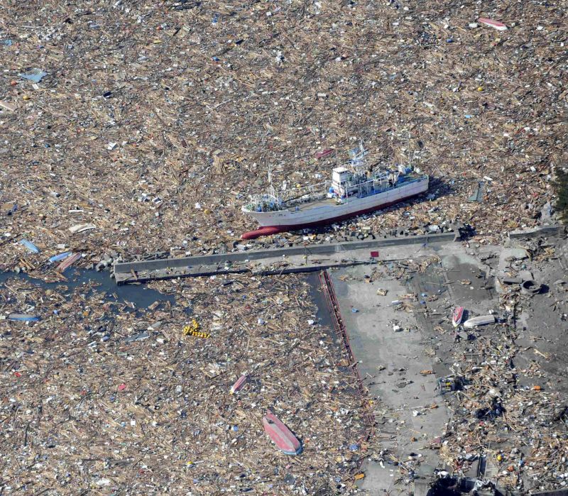 Barco de pesca cercado de escombros na cidade de Kamaishi, um dia depois que o terremoto de 8,9 de magnitude atingiu a região, seguido de um tsunami. A tragédia aconteceu no dia 11 de março deste ano | Yomiuri Shimbun/AFP
