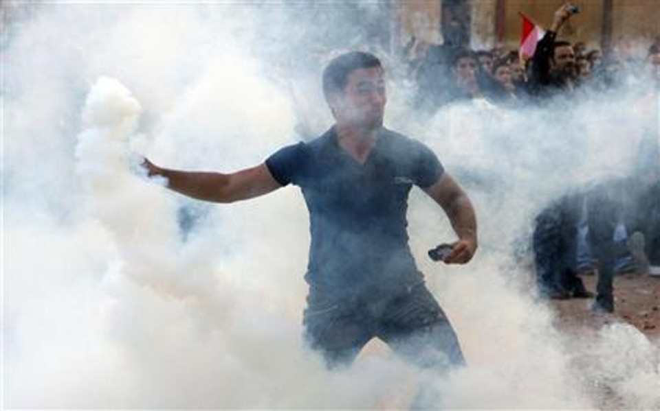 Homem foge depois de polícia atirar gás lacrimogêneo durante confrontos entre cristãos coptas e moradores do bairro de Shoubra, no Cairo | REUTERS/Stringer