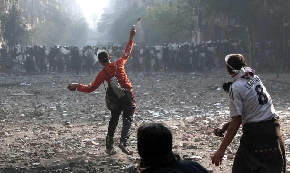 Protestante egípcio jopga pedra contra a polícia que tenta conter violência durante protestos no Cairo | AFP PHOTO / MAHMUD HAMS