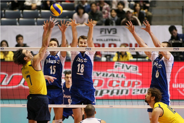 O paranaense Giba encara o bloqueio polonês formado por Zygadlo, Mozdzonek e Kurek na penúltima rodada da Copa do Mundo | FIVB/ Divulgação