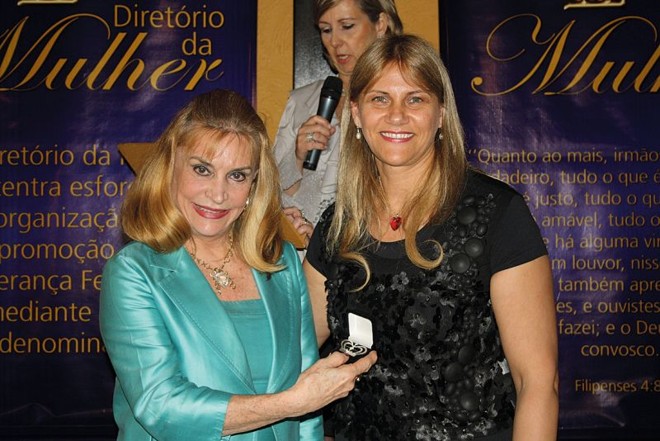 MERECIDA HOMENAGEM- O Diretório da Mulher, organização vinculada ao Ministério da Comunhão Cristã ABBA, realizou agradável chá da tarde, prestando merecidas homenagens a Lylian Vargas e Beatriz Séra. Na foto, Lylian, que possui expressivo currículo, é parabenizada pela diretora da entidade, Roseli Zadureski de Carvalho |