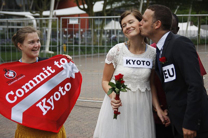 Noivo representando a União Europeia beija a noiva Kyoto em um casamento falso feito por manifestantes para pedir o compromisso europeu com as questões climáticas | Ally Carnwath/AFP