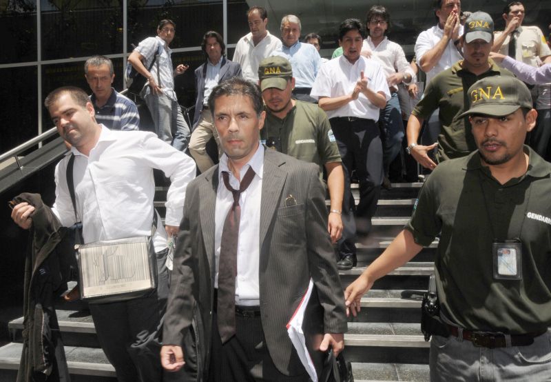 O juiz Walter Bento (centro), que determinou a intervenção na Cablevisión, deixa a sede da emissora em Buenos Aires, após fazer buscas de documentos | Juan Vargas/AFP