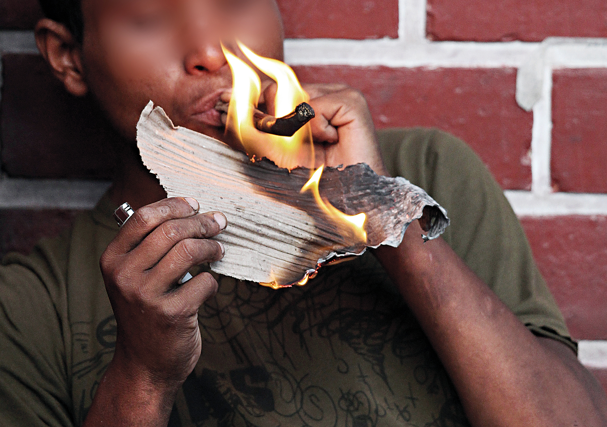 Na Rua Lamenha Lins, no Centro de Curitiba, usuário de crack acende cachimbo com o auxílio de um papelão em chamas | Walter Alves/Gazeta do Povo