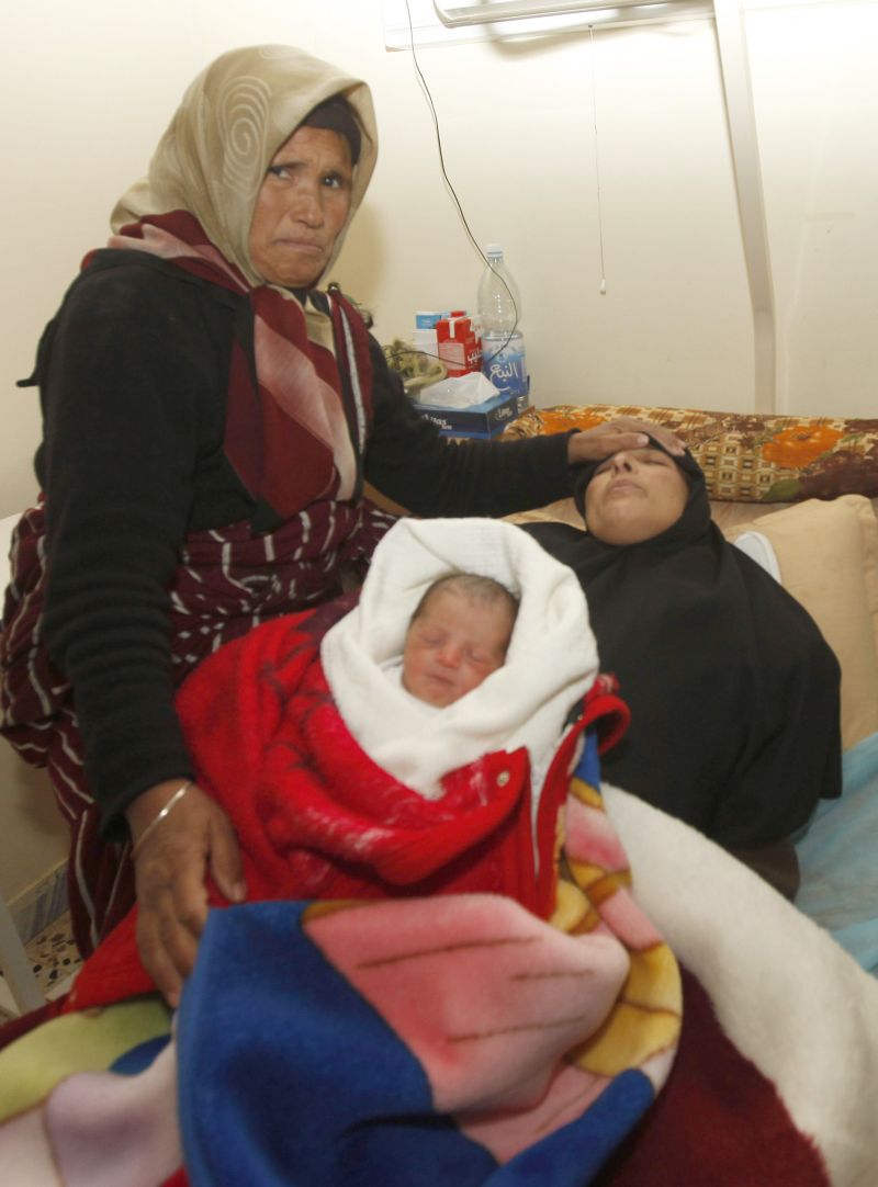 Mulher de Ezzedine al-Ghool (à dir.), homem torturado até a morte na cidade de Gharyan, é consolada pela mãe. O bebê na foto é Ali, filho do casal, nascido três dias depois do assassinato do pai | Ismail Zitouny/Reuters