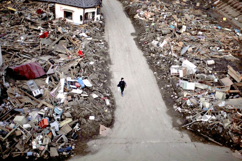 Mulher caminha por área destruída pelo terremoto seguido de tsunami no Japão em 11 de março do ano passado | Carlos Barria/Reuters