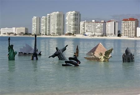 Minituaras de símbolos turísticos internacionais feitas com papelão são colocados no mar numa praia de Cancún em manifestação do Greenpeace contra o aquecimento global | Reuters