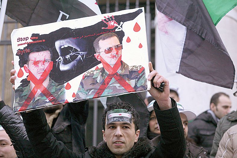 Cartaz faz alusão à tortura e rejeita o ditador sírio Bashar al-Assad | Geertje De Waegeneer/AFP