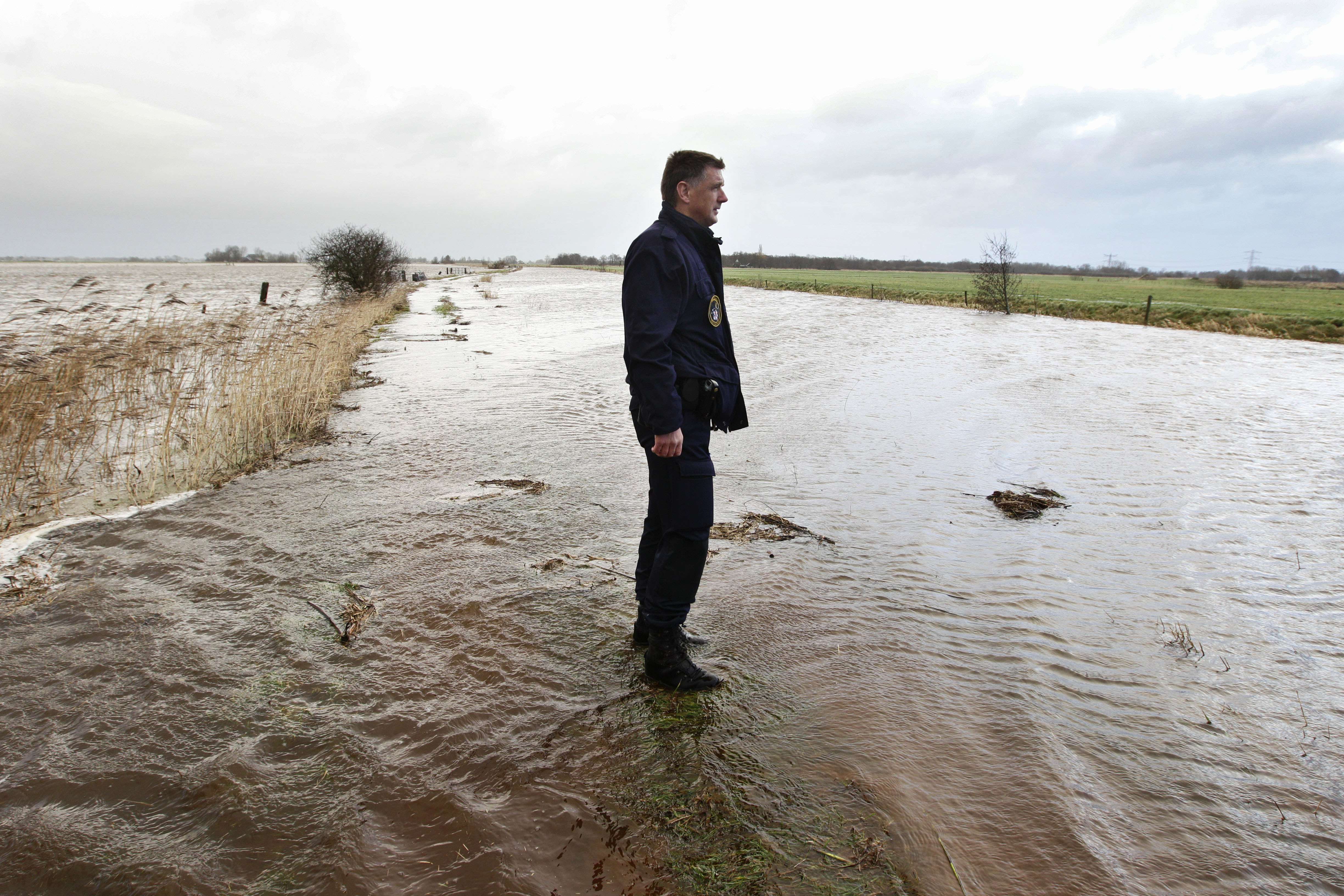 Policial holandês observa a água que toma conta de dique na cidade de Tolberter Petten | AFP PHOTO / ANP / VINCENT JANNINK