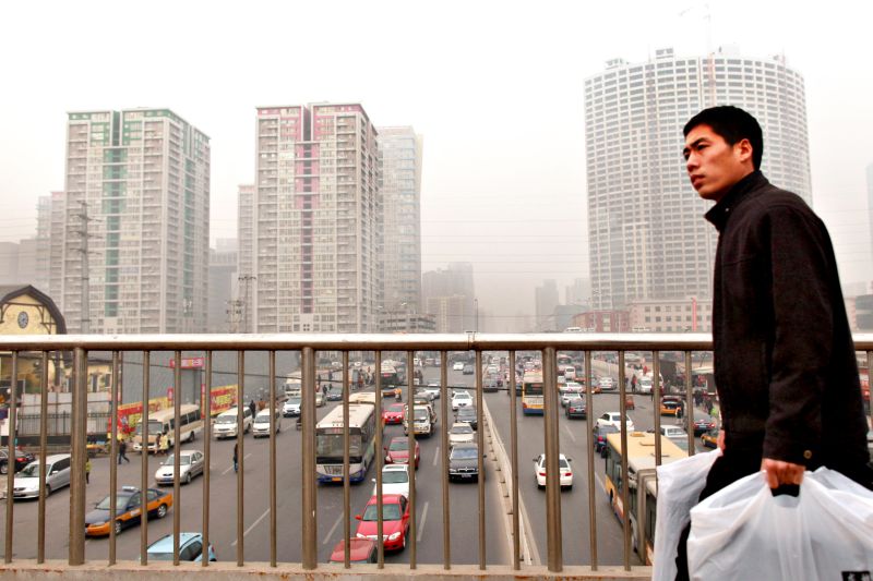 Homem caminha por viaduto diante de prédios de apartamentos em Pequim: crescimento urbano terá impacto sobre a economia e o meio ambiente chineses | Ed Jones/AFP