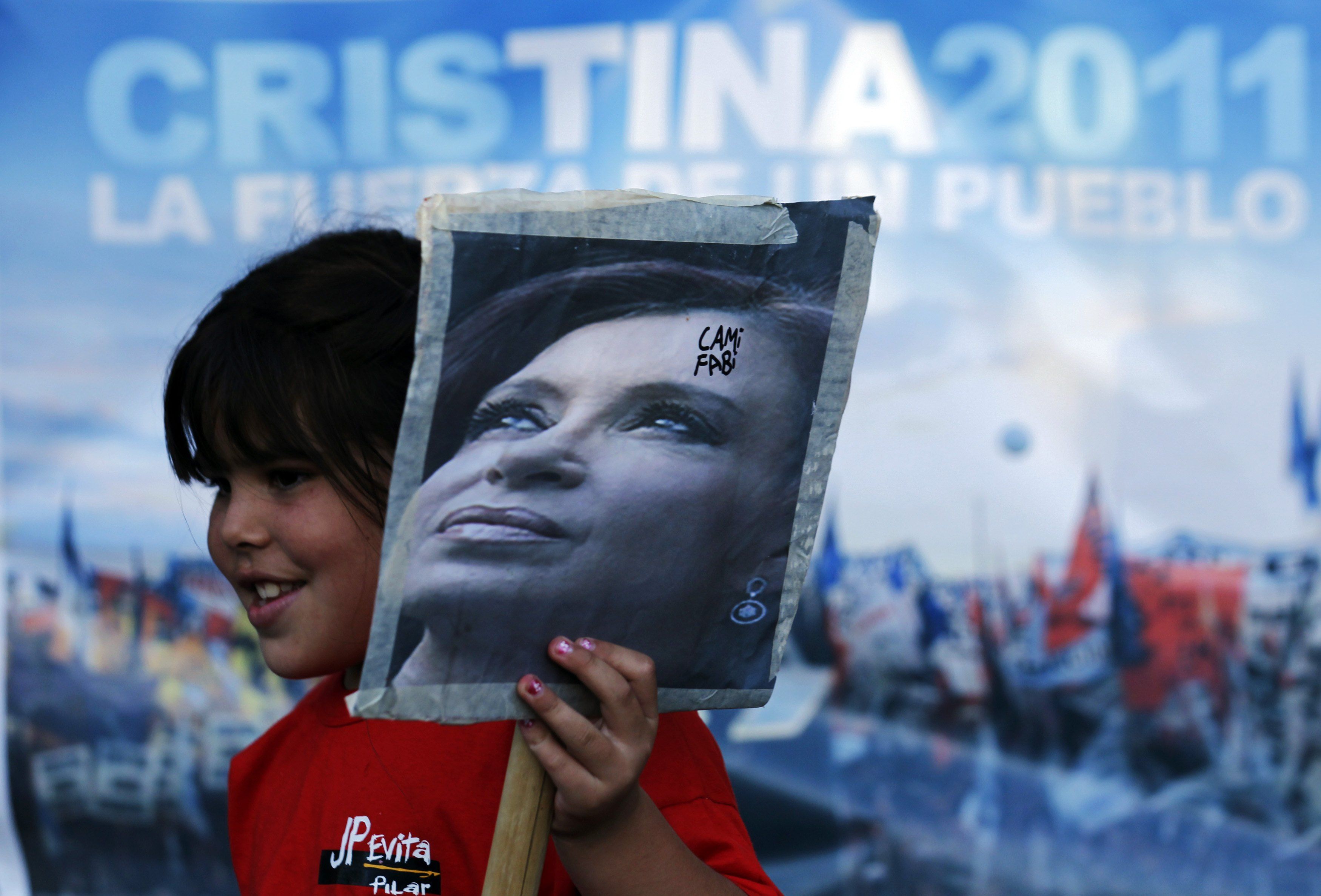 Menina segura retrato da presidente argentina Cristina Kirchner em frente a hospital onde ela será operada | REUTERS/Marcos Brindicci
