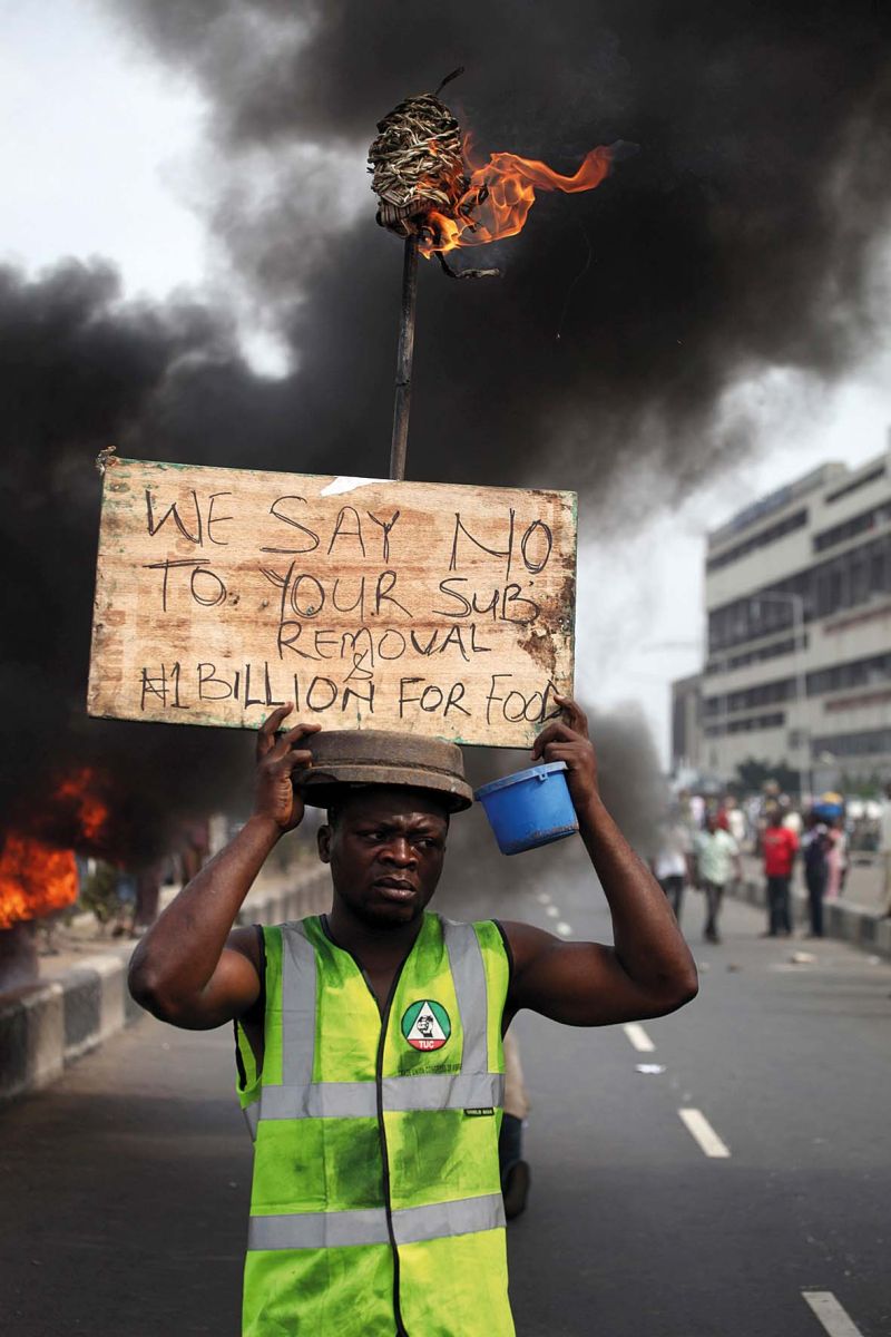 Manifestante carrega cartaz que diz: Nós dizemos não ao fim do subsídio e ao 1 bilhão de nairas [referência ao valor, equivalente a US$ 6,2 milhões por ano, que o presidente Goodluck Jonathan recebe como auxílio alimentação para sua família] | Akintunde Akinleye/Reuters