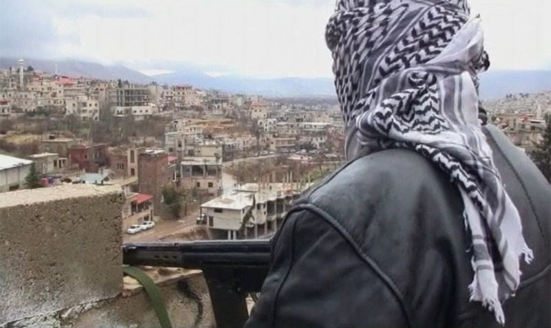 Membro do Exército Livre da Síria com rifle na mão durante patrulha na cidade de Zabadani | REUTERS/Amateur video via Reuters TV