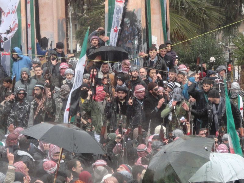 Soldados sírios que desertaram as forças do governo para se unir aos rebeldes são vistos junto aos manifestantes durante protesto contra o presidente Bashar al-Assad em Idlib nesta terça | REUTERS/Handout