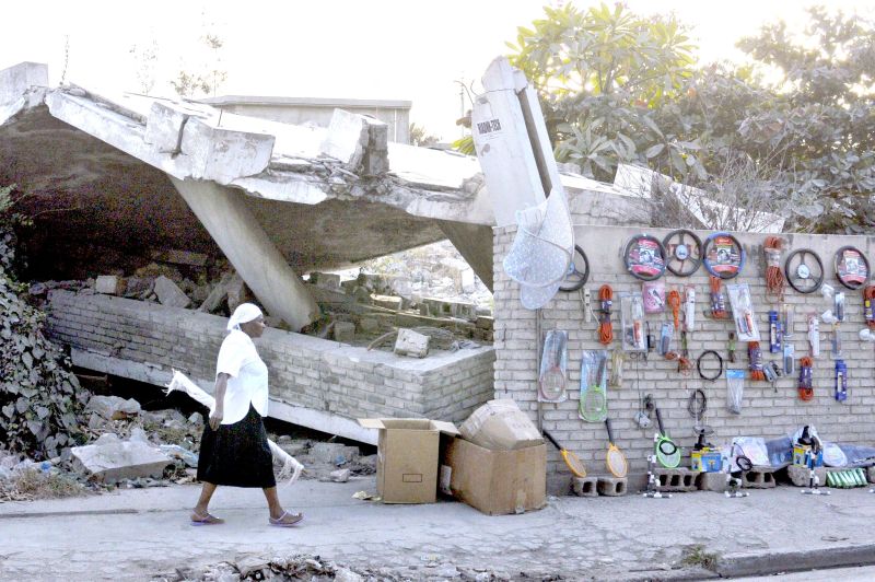 Mulher caminha diante de prédio destruído em Porto Príncipe, de onde haitianos saem para tentar a vida em cidades menores | Swoan Parker/Reuters