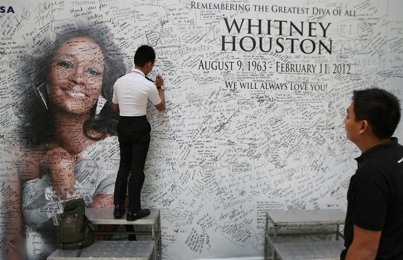 Um fã assina uma mensagem em um mural com a imagem da cantora Whitney Houston em Quezon, a leste de Manila, nas Filipinas | EFE / Rolex Dela Pena