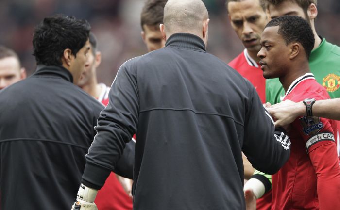 Suárez (de casaco preto, à frente) não cumprimenta Evra no reencontro dos dois após o francês acusar o uruguaio de racismo | Darren Staples / Reuters