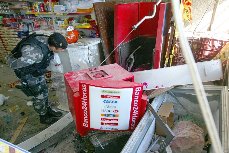Policial avalia estragos causados ao caixa eletrônico de um supermercado em Campo Magro, na região metropolitana de Curitiba | Anderson Tozato/Tribuna do Paraná