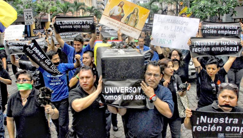 Funcionários do jornal El Universo marcham em Quito carregando um caixão falso em protesto contra a condenação de executivos da empresa e jornalista | Camilo Pareja/AFP