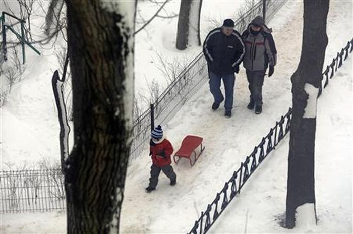 Uma família passa por uma alameda coberta de neve em Bucareste, na Romênia, nesta quinta-feira | Reuters