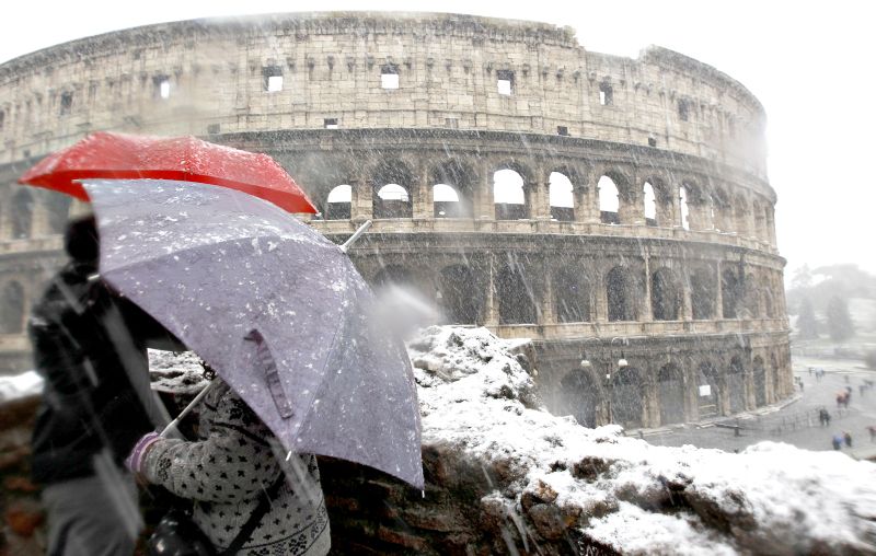 Turistas usam guarda-chuvas para se proteger da neve em frente do Coliseu, que foi fechado | Alessandro Bianchi/Reuters