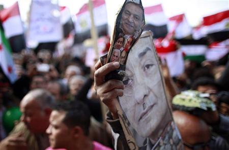 Um manifestante segura sapato com fotos do Marechal Mohamed Hussein Tantawi e membros do velho regime durante um protesto que exige que o Exército transfira o poder para civis, na Praça Tahrir | REUTERS/Suhaib Salem