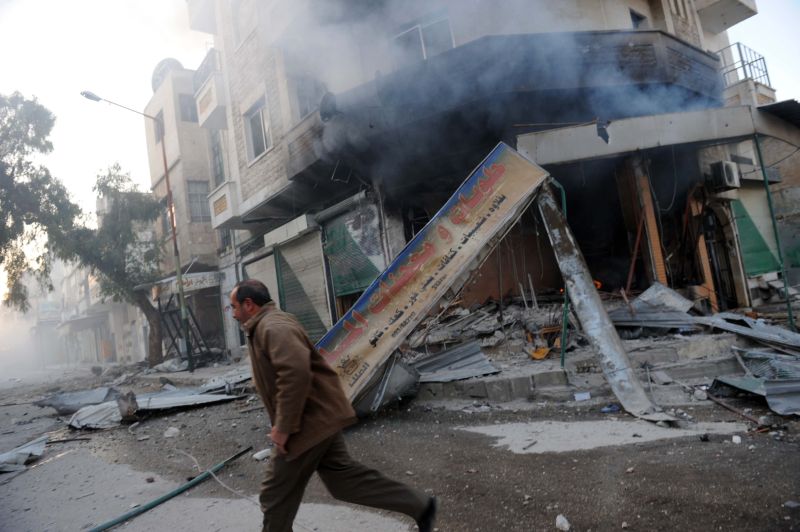 Homem passa por prédio em chamas na cidade de Idlib, na Síria | AFP PHOTO/BULENT KILIC