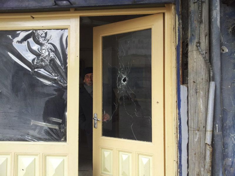 Homem observa rua de dentro de sua casa atingida por tiros no bairro Bab Sabaa, em Homs | REUTERS/Moulhem Al-Jundi/Handout