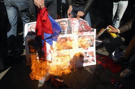 Países ocidentais e árabes responderam com indignação após o veto da Rússia e da China à resolução do Conselho de Segurança das Nações Unidas pedindo que o presidente sírio Bashar al-Assad deixasse o poder. Na foto, manifestantes em Beirute queimam bandeiras russa e chinesa e um poster com fotos de Assad e do premiê russo, entre outros | REUTERS/Stringer