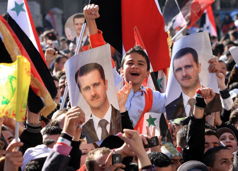 Populares seguram retratos do presidente sírio Bashar al-Assad em manifestação a favor do governo. Por outro lado, confrontos deixaram mais mortos no país | Louai Beshara/AFP