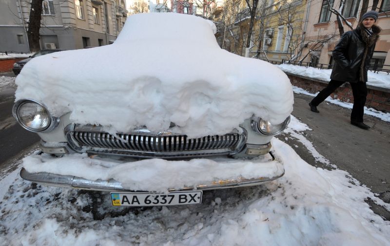 Homem observa carro coberto de neve em Kiev, Ucrânia, onde as temperaturas chegaram a -20ºC | Sergei Supinsky/AFP