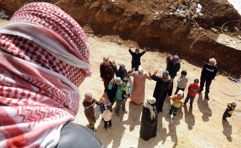 Sírios que fugiram da violência acenam para fotógrafo na cidade de Arsal, no Líbano | Wael Hamzeh/Efe